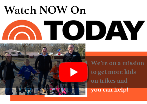 A group of people standing next to a sign on youtube, watch now on today we're on a mission to get more kids on trikes and you can help!